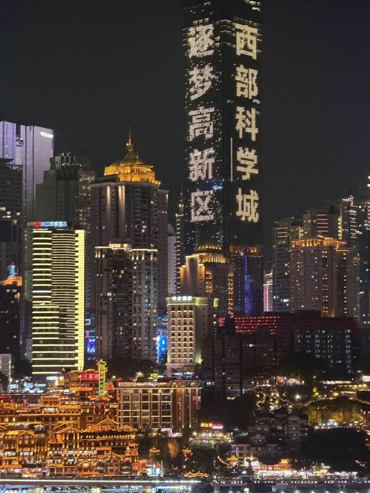 Hongyadong lit up at night under a tower with glowing Chinese characters