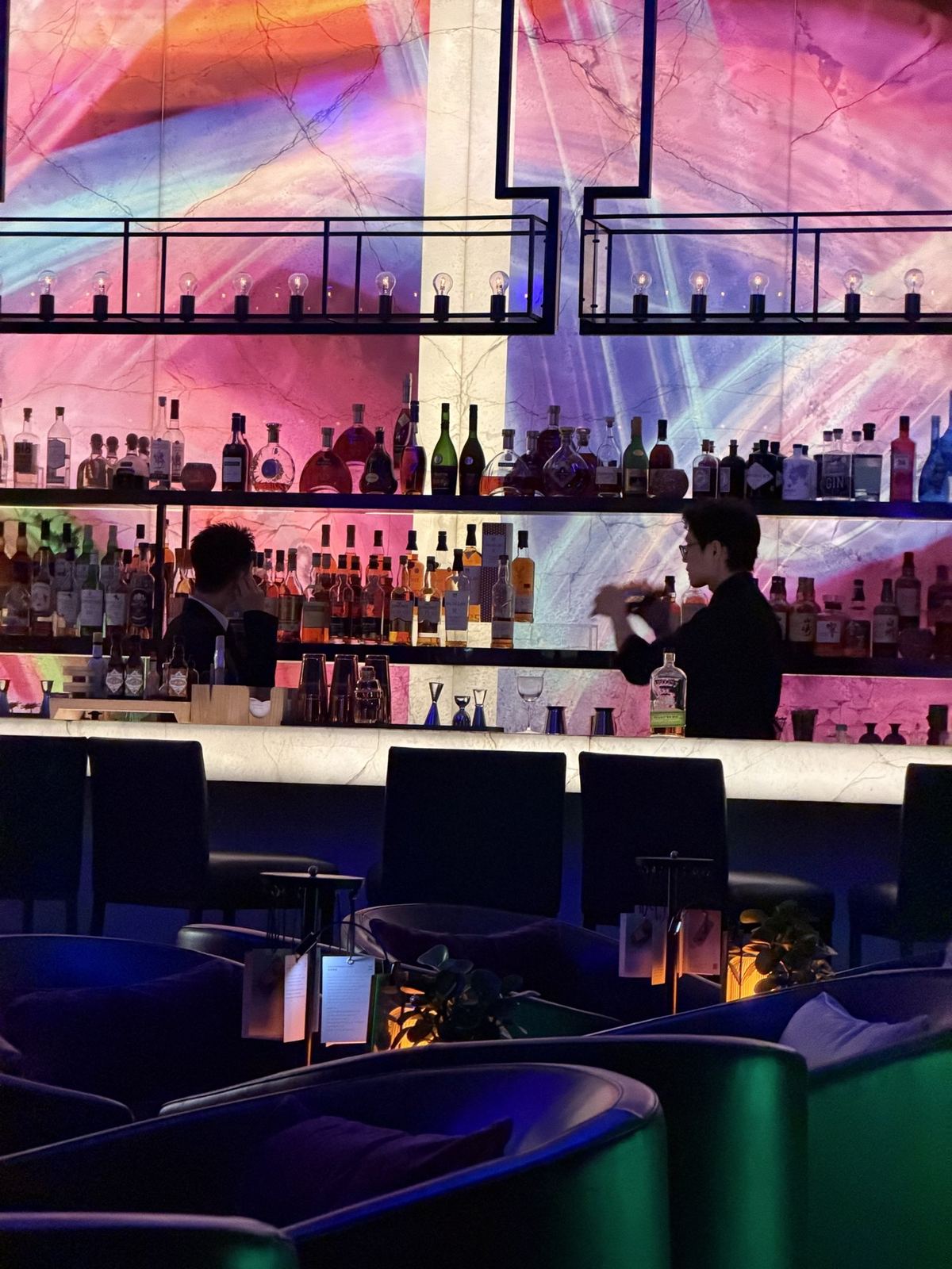 A cocktail bar lit in pink and purple inside the SHUA sky bar, Chongqing