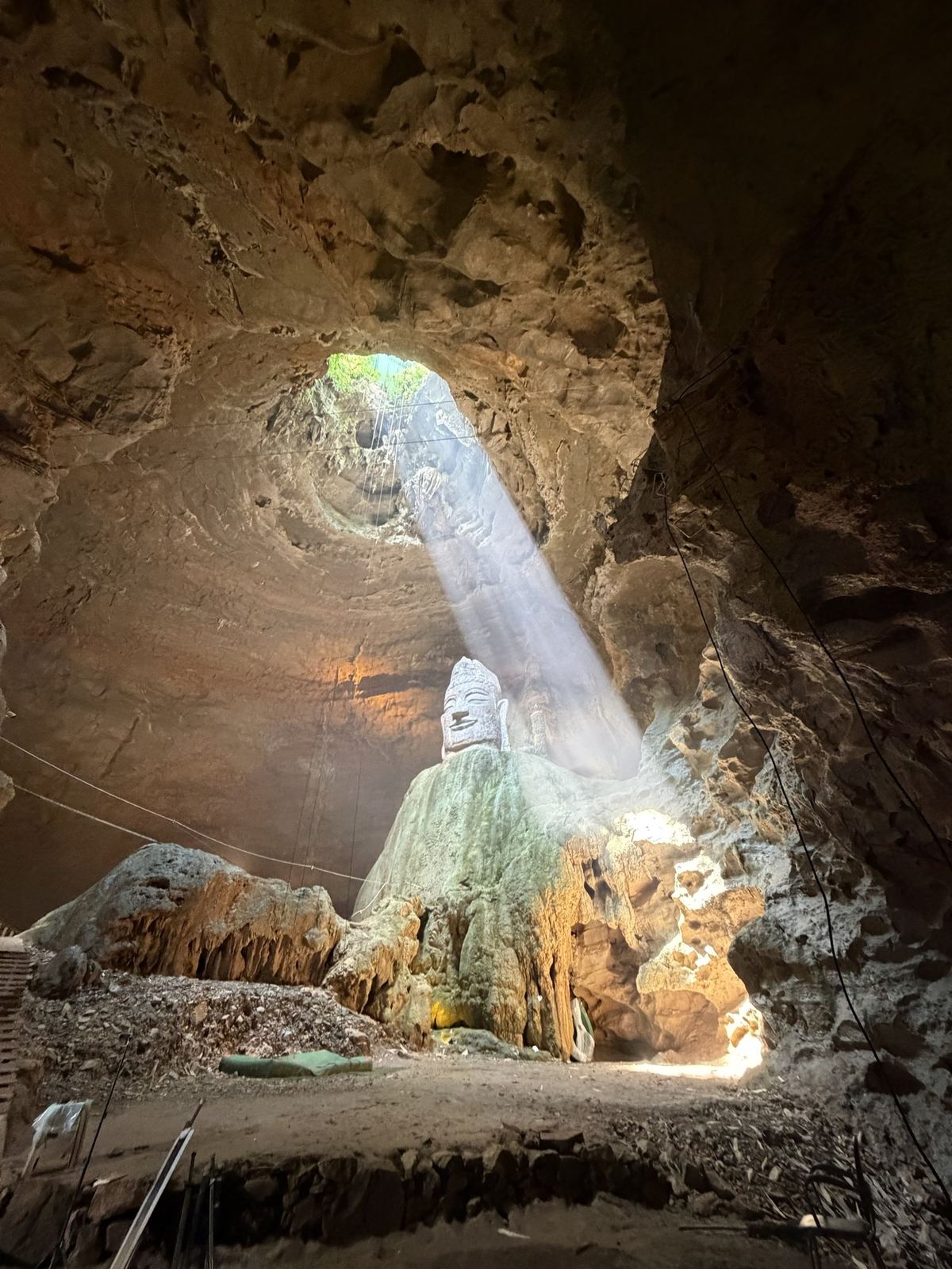 A beam of sunlight through the opening of Tianyan Cave onto a giant stone Buddha