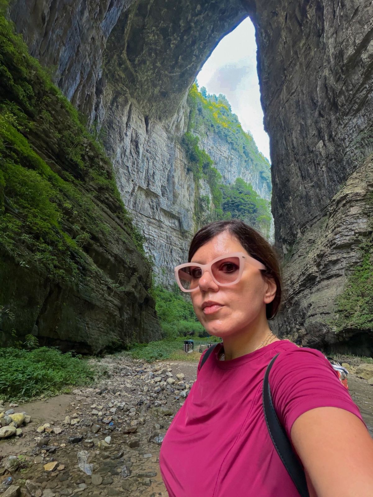 Linda under the huge stone arch of a natural bridge in Wulong