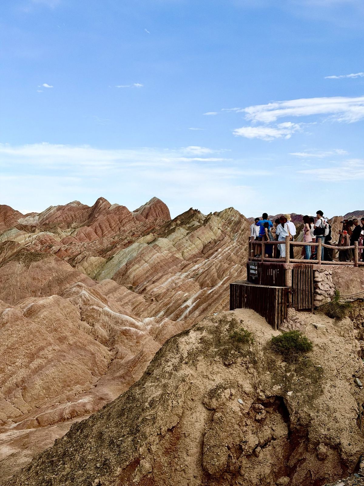 Visitors on a wooden viewing platform above striped red and green ridges at the Zhangye Danxia