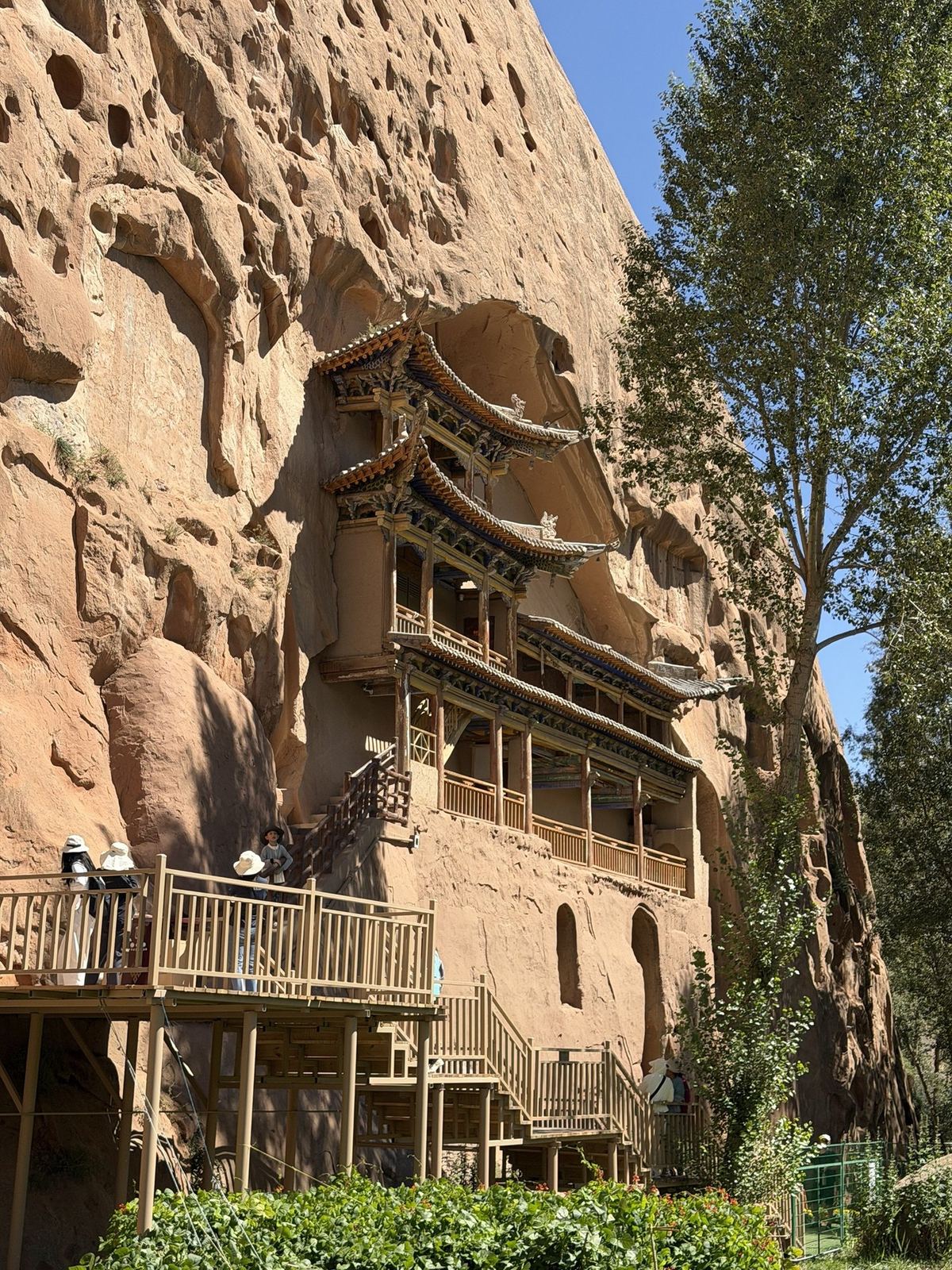 Wooden halls built into the red sandstone cliff at Mati Temple, reached by steep wooden stairs