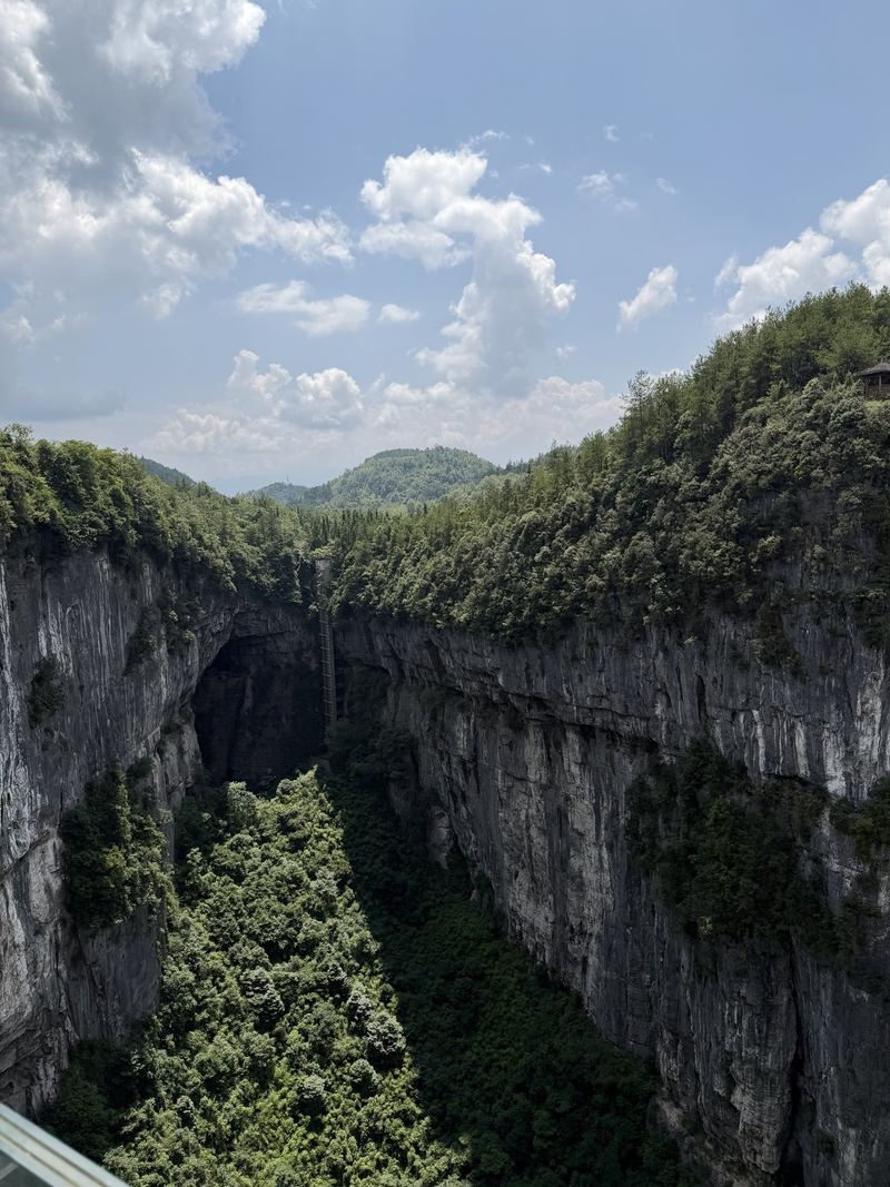 A huge karst sinkhole in Wulong seen from a glass platform, with a lift on the cliff