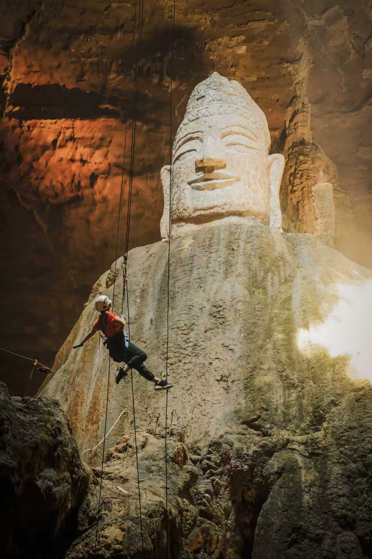 Linda abseiling past the giant stone Buddha in Tianyan Cave