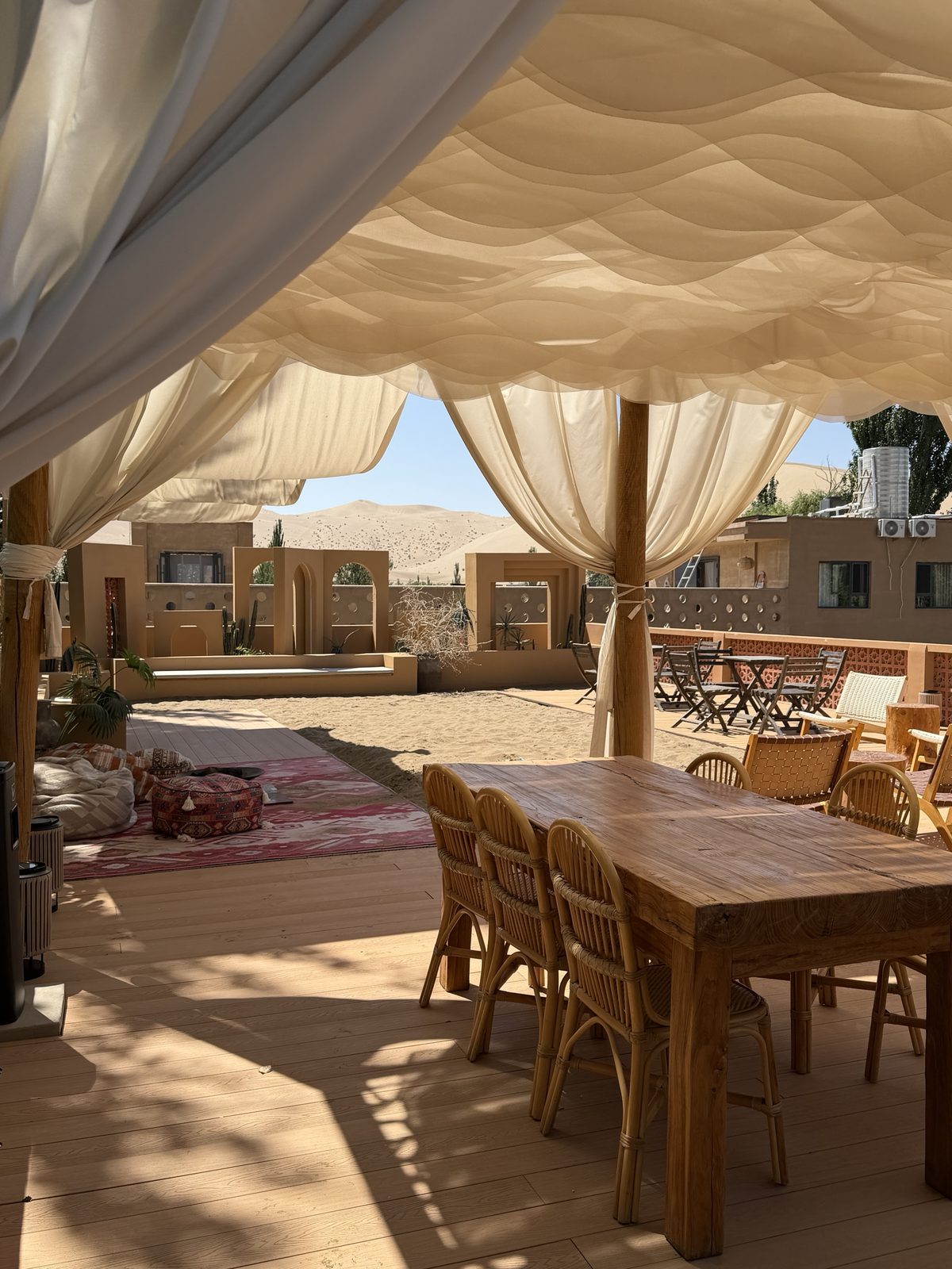 Shaded terrace with curtains and the Mingsha Shan dunes behind, Boman Oasis Resort, Dunhuang