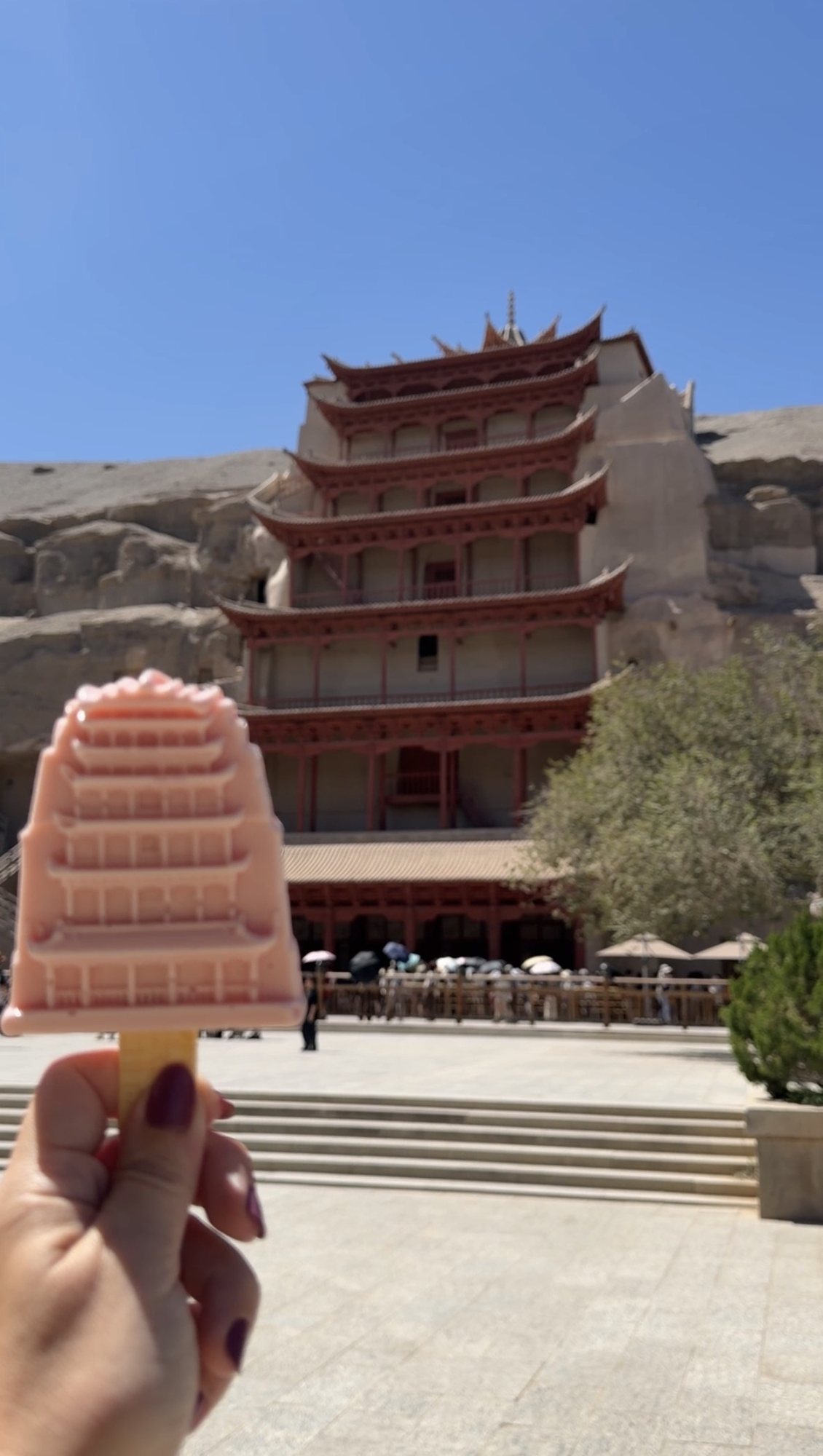 An ice cream shaped like the Nine Storey pagoda, held up in front of the real one at Mogao