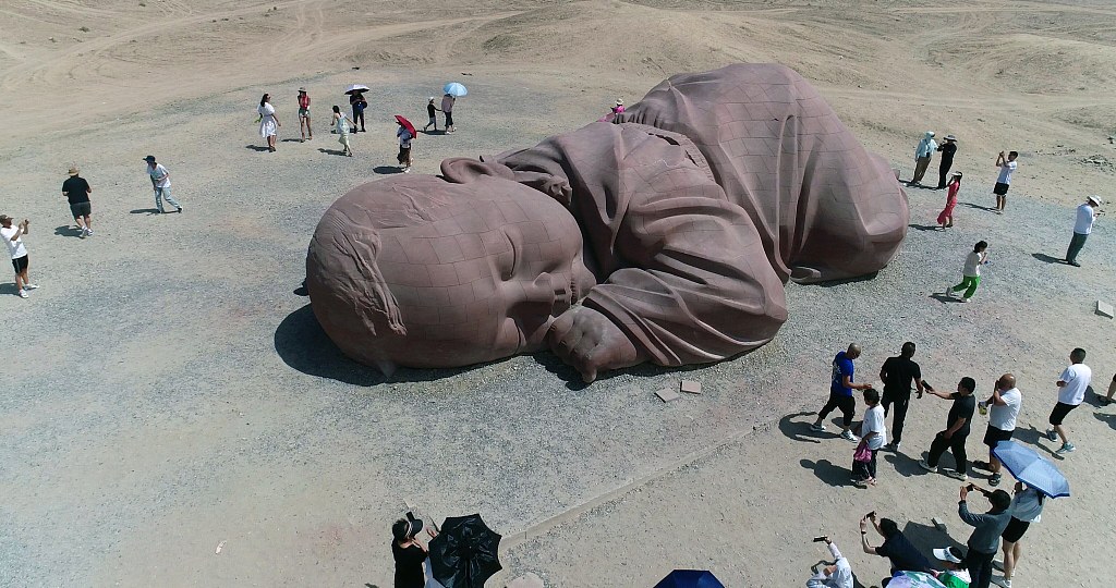 Son of the Earth, a giant red sandstone sleeping baby in the Gobi desert of Guazhou, with visitors around it