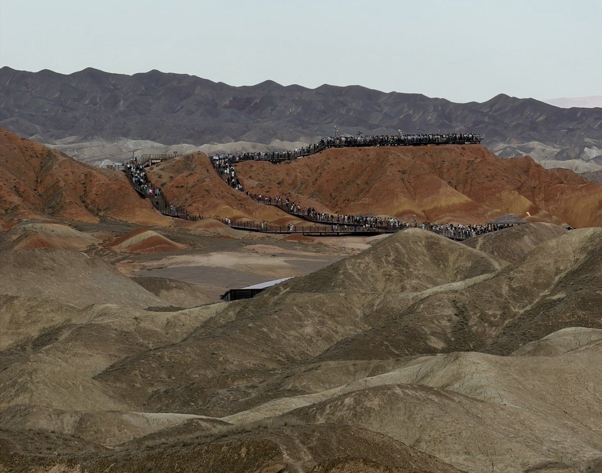 Crowds of visitors along the boardwalks over the red ridges of the Zhangye Danxia Rainbow Mountains